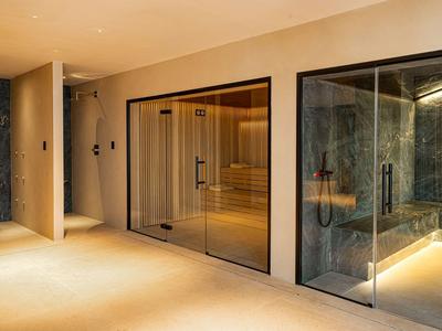 Moderner Hotel-Spa-Bereich mit Sauna und Dampfbad aus Glas und warmem Licht.