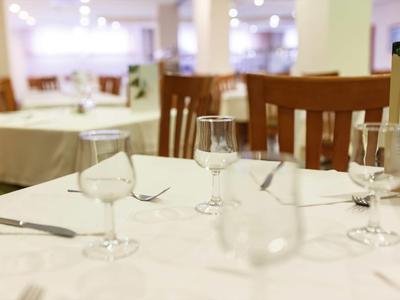 Ein gedeckter Esstisch mit Gläsern, Besteck und weißen Tischdecken in einem Restaurant.