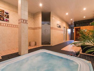 Indoor area with hot tub, showers, and seating area in a hotel.
