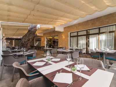 Outdoor restaurant area with set tables and modern furniture under a covered roof.