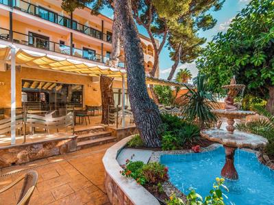 Hotel outdoor area with swimming pool, fountain, and shaded trees.