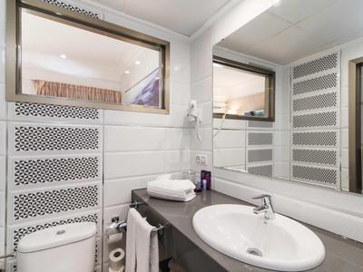 Modern bathroom with white wall tiles, large mirror, and sink on gray countertop.