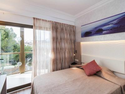 Bright hotel room with double bed, balcony, and modern decor.