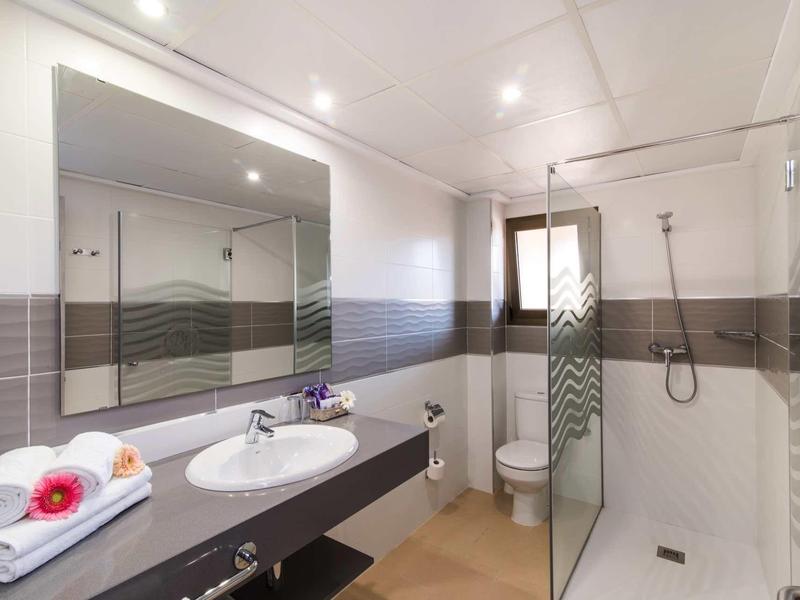 Clean, modern bathroom with large shower, sink, toilet, and mirror in hotel.