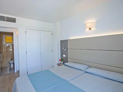 Une chambre d'hôtel simplement meublée avec un lit double et une salle de bain avec douche.