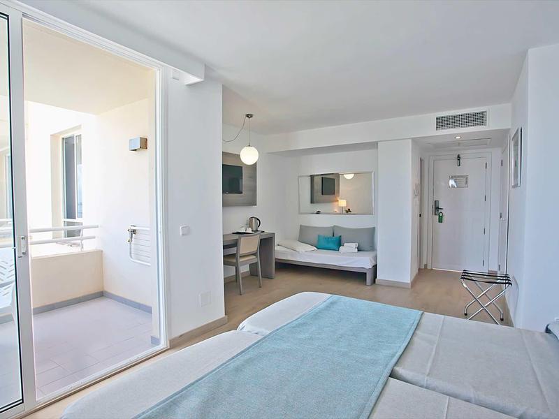 Chambre d'hôtel lumineuse avec lit double, bureau, balcon et mobilier moderne.