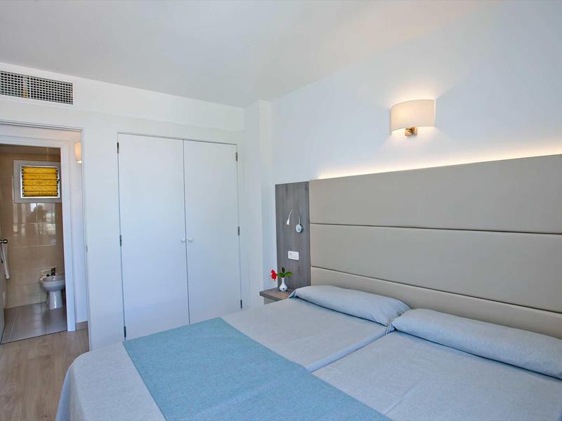 Une chambre d'hôtel simplement meublée avec un lit double et une salle de bain avec douche.