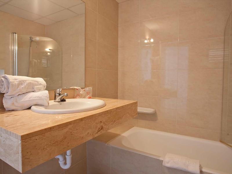 Petite salle de bain avec lavabo, serviettes et baignoire avec rideau de douche.