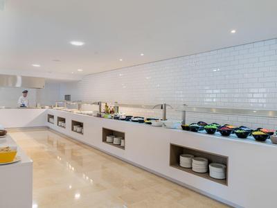 Cucina d'hotel moderna e minimalista con piastrelle bianche e ampia superficie di lavoro.