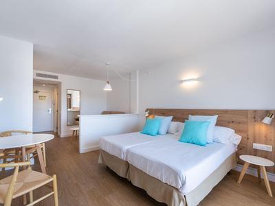 Camera d'hotel luminosa con due letti, pavimento in legno e mobili moderni.