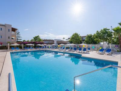 Großer Außenpool mit Liegestühlen und Sonnenschirmen unter klarem Himmel in einem Hotelresort.