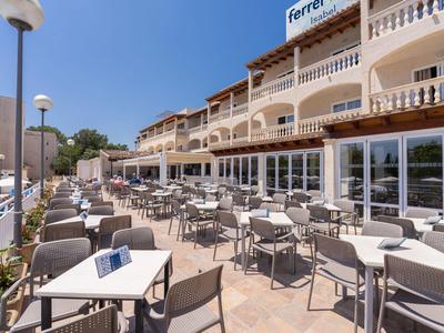 Ampia terrazza con tavoli e sedie davanti a un hotel sotto un cielo sereno