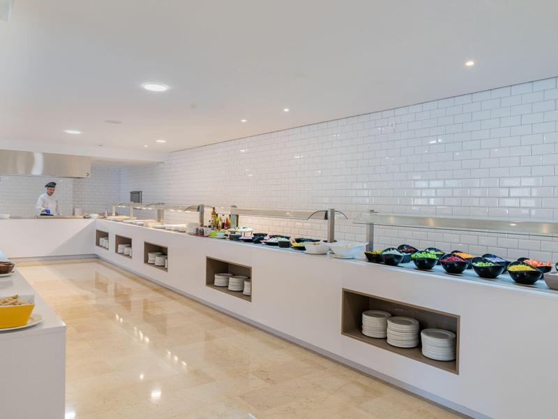 Cucina d'hotel moderna e minimalista con piastrelle bianche e ampia superficie di lavoro.