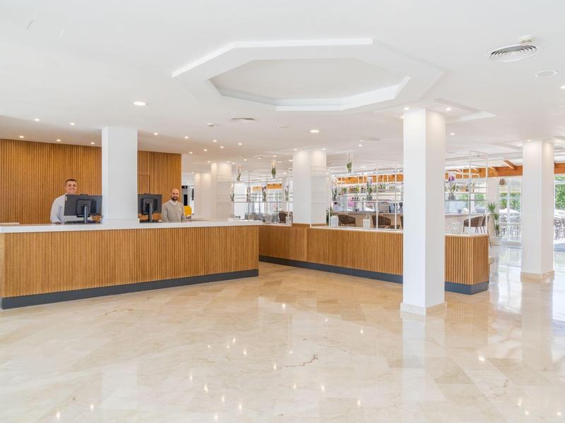 Area reception dell'hotel luminosa con banconi in legno e pavimento in marmo.