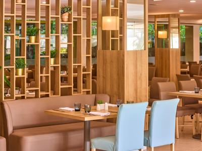 Moderner Restaurantraum mit Holzwänden und bequemen Sitzgelegenheiten in warmem Licht.