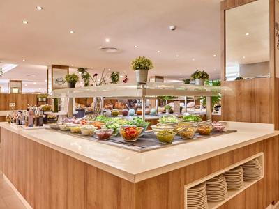 Modernes Buffet mit frischem Gemüse, Obst und Salaten in einem hellen Restaurant.