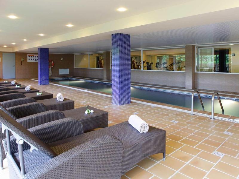 Piscina interior moderna con tumbonas y toallas en un hotel.