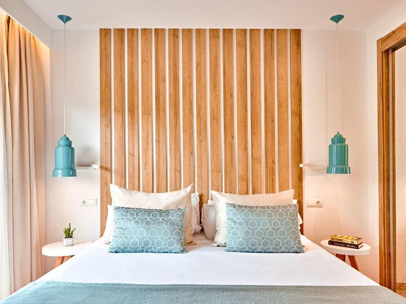 Modernes Hotelzimmer mit hellem Holzakzent, Doppelbett und blauen Akzentlampen an den Wänden.