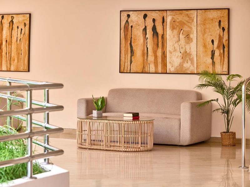 Helles Wartezimmer mit Couch, Bambustisch, Pflanzen und abstrakten Wandbildern.