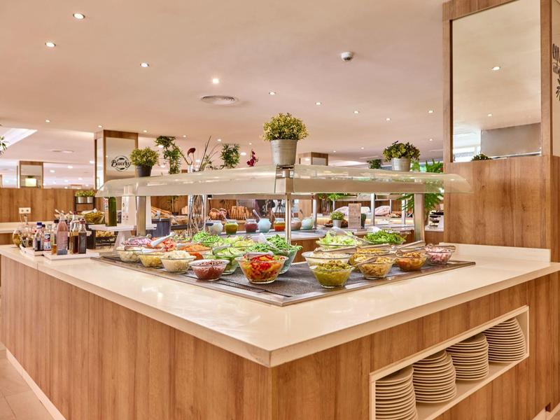 Modernes Buffet mit frischem Gemüse, Obst und Salaten in einem hellen Restaurant.