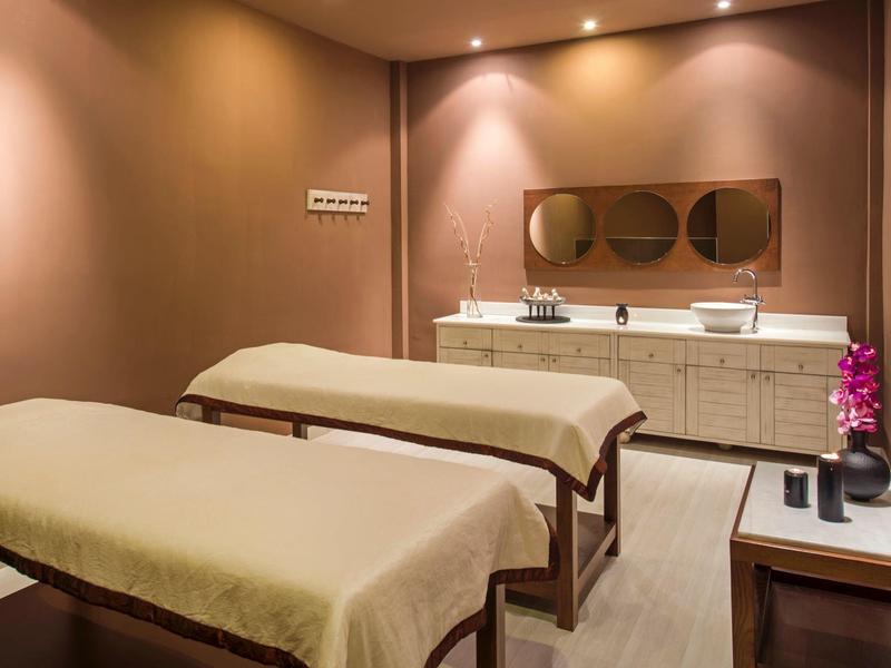 Pokój zabiegowy z dwoma stołami do masażu i kojącym oświetleniem.