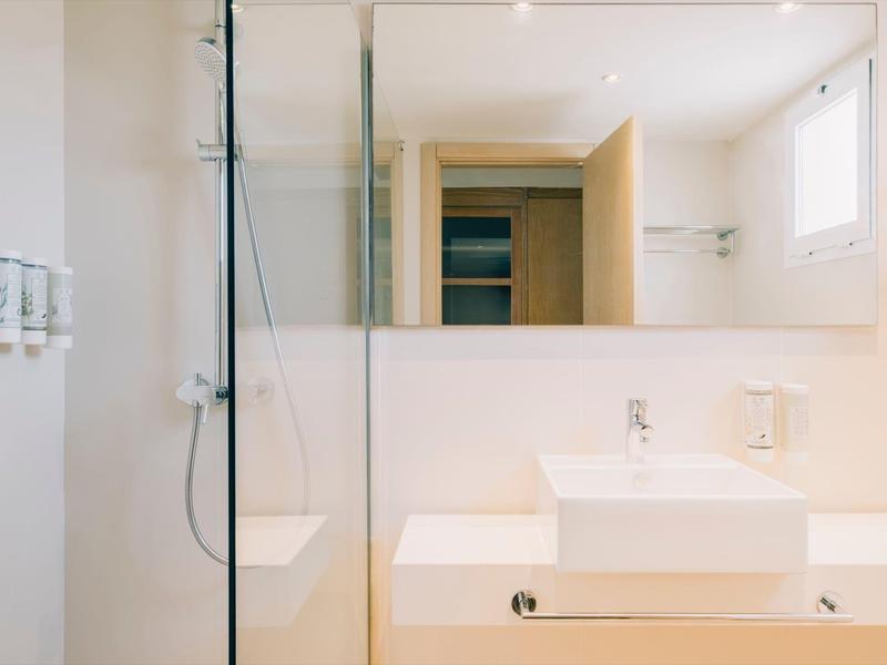 Jasna, nowoczesna łazienka z dużym lustrem, umywalką i kabiną prysznicową.