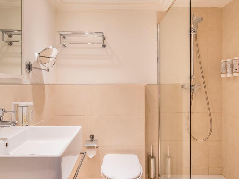 Jasna, nowoczesna łazienka z umywalką, toaletą i prysznicem bez brodzika.