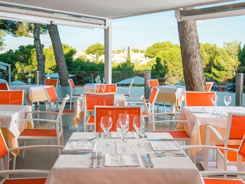 Nowoczesna jadalnia z pomarańczowymi krzesłami i nakrytymi stołami w świetle dziennym.