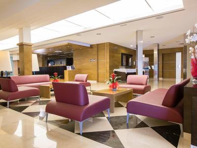 Modern hotel lobby with purple sofas, marble floor, and warm lighting.