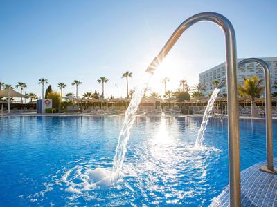Pool with water spout and sunlight in the background on a sunny day.
