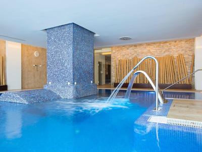 Indoor pool with water feature and stairs in a wellness area.