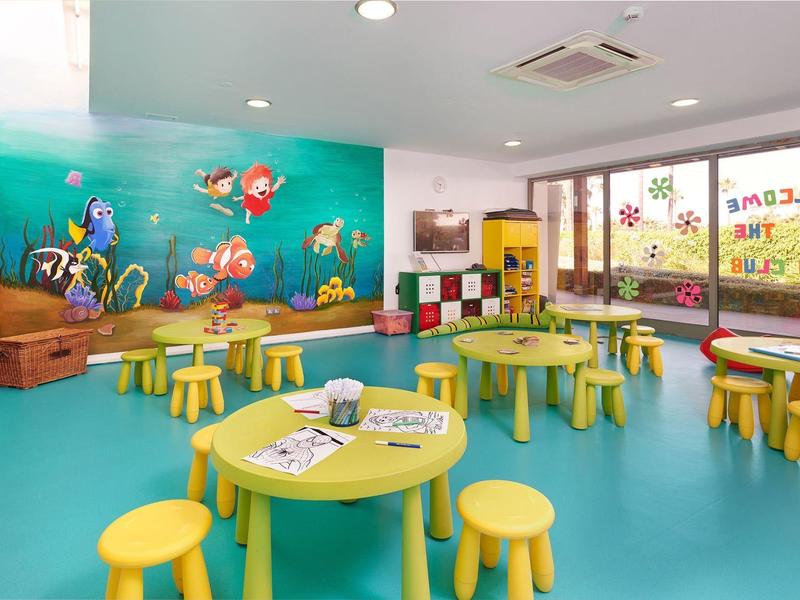 Colorful kids' playroom with underwater wall mural and small tables with stools.