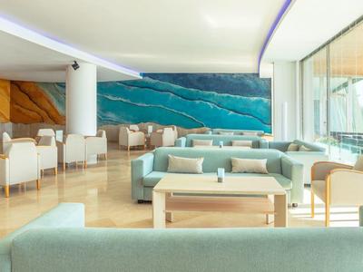 Ampio lounge moderno e luminoso con divani blu, poltrone bianche e grande opera d'arte murale.