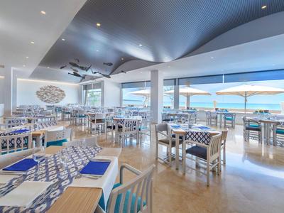Ristorante luminoso con mobili bianchi e vista sul mare attraverso grandi finestre
