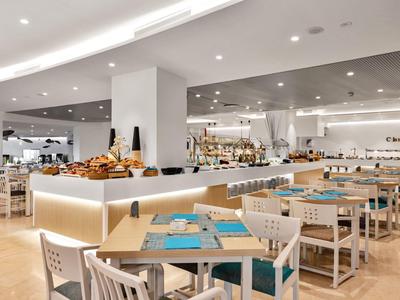 Helles, modernes Restaurant mit weißen Möbeln und Snackbereich in der Mitte.