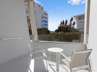Balcone con due sedie bianche e un piccolo tavolo rotondo in un hotel.