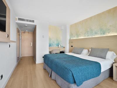 Camera d'hotel moderna con letto matrimoniale, pavimento in legno e decorazione astratta sopra il letto