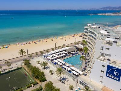 Hotel sulla spiaggia con piscina, lettini e vista sul mare blu e sulla sabbia.
