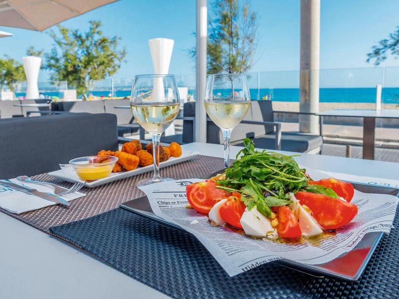 Un tavolo apparecchiato con insalata e bevande su una terrazza con vista mare.