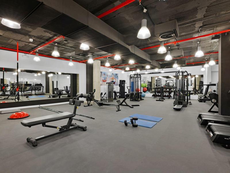 Ampia palestra con varie attrezzature da allenamento, tappetini e pesi con design moderno.