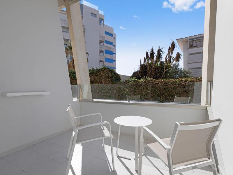 Balcone con due sedie bianche e un piccolo tavolo rotondo in un hotel.