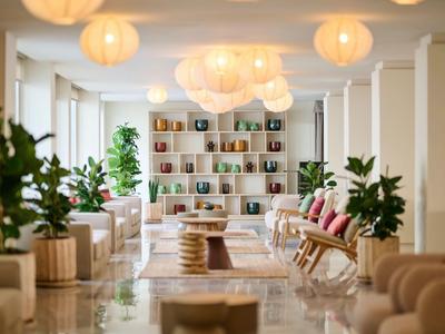 Světlý, stylově zařízený lounge prostor s rostlinami, sezením a kulatými stropními lampami.