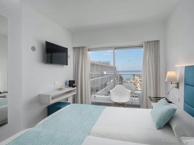 Moderní hotelový pokoj s manželskou postelí, TV, balkónem a výhledem na moře.