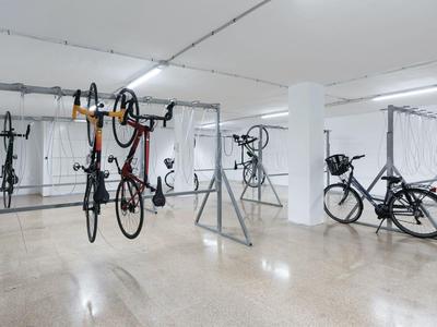 Místnost pro uskladnění kol s několika zavěšenými a odstavenými koly v dobře osvětleném prostoru.