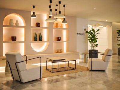 Moderní hotelová lounge se dvěma křesly, stolem a dekorativními policemi.