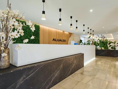 Moderní hotelová recepce s bílým pultem, dřevěným obkladem a rostlinami