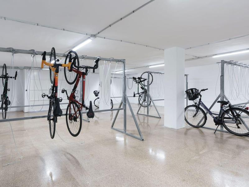 Sala biciclette luminosa con diverse bici appese e parcheggiate.