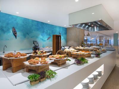 Buffet mit vielfältigem Gebäck auf Holztabletts in modernem, hellem Restaurantambiente.