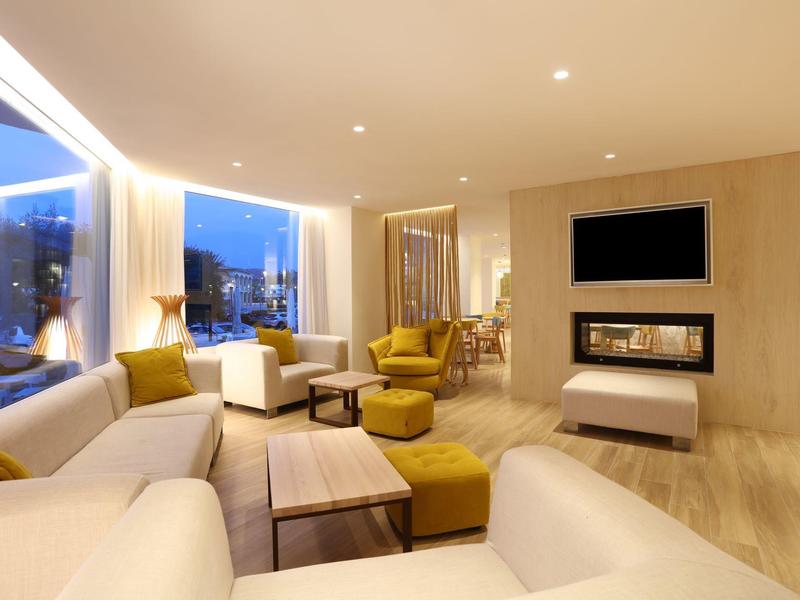 Modernes Wohnzimmer mit gemütlichen Sofas, gelben Sesseln, Holztisch und Kamin unter Fernseher.