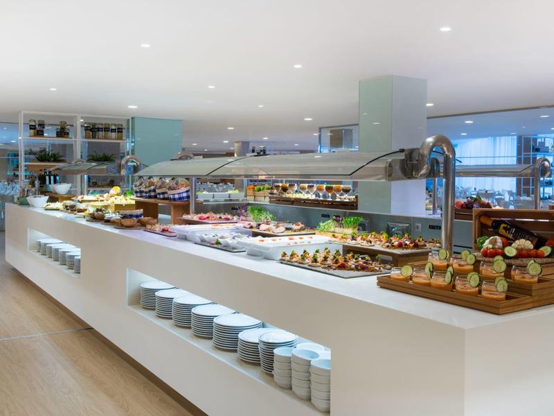 Moderne Buffetinsel mit vielfältigem Frühstücksangebot, helle Einrichtung, klare Linien und große Fenster.